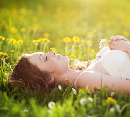 Wohlbefinden mit heilusan: Frau liegt entspannt auf dem Gras